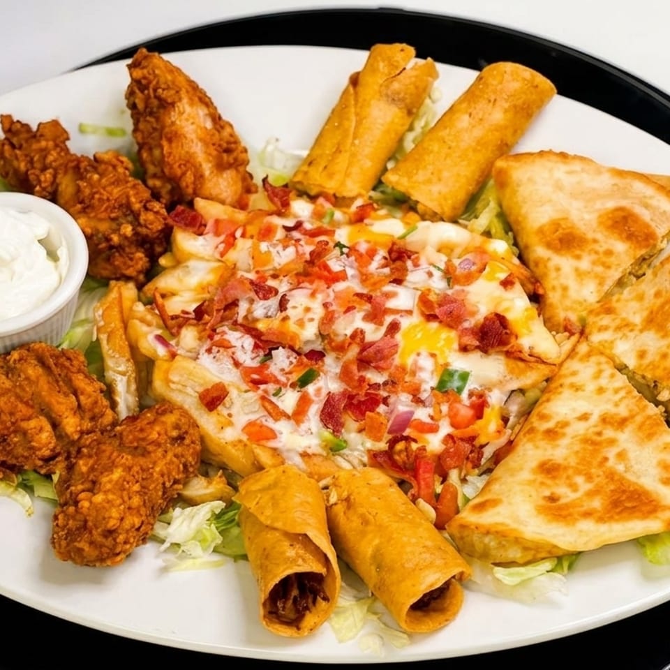 A large platter of fried chicken, loaded fries, quesadillas, and taquitos with a side of sour cream.